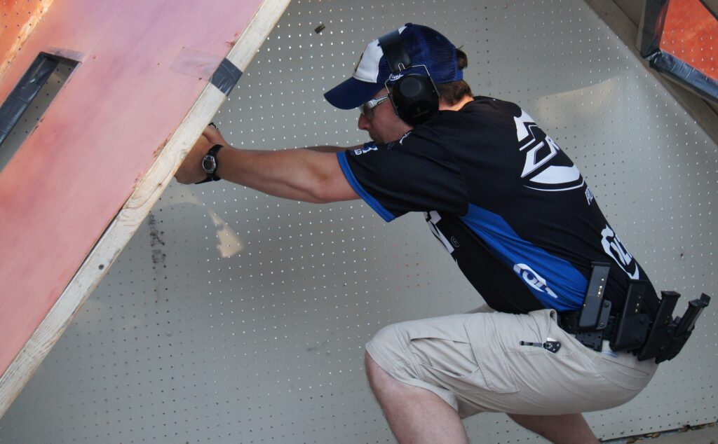Caleb crouched down shooting at a USPSA match