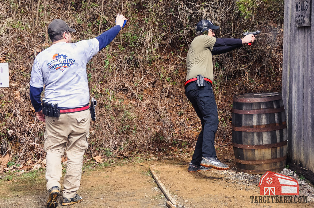 a carry optics shooter shooting a stage under the watchful eye of a range officer