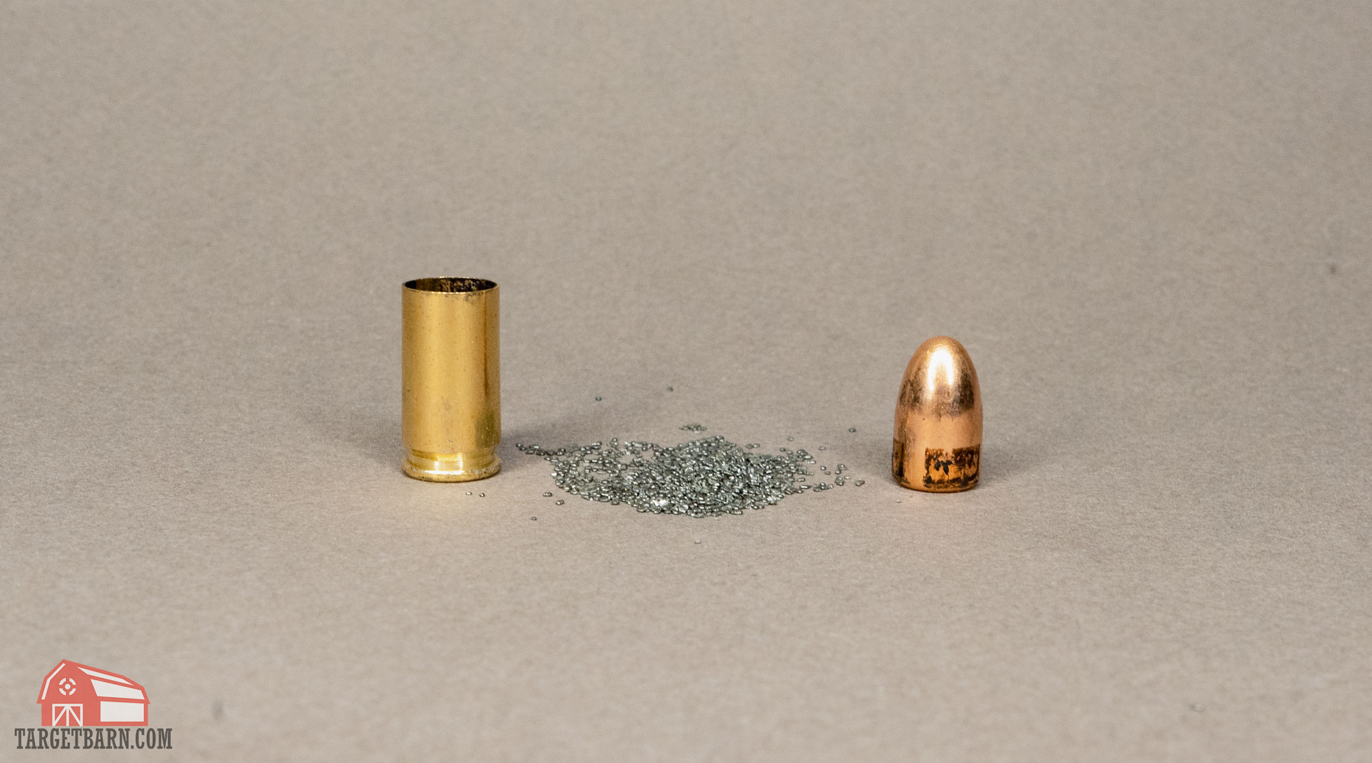 an empty casing next to the powder from a cartridge and the bullet showing the components of a cartridge