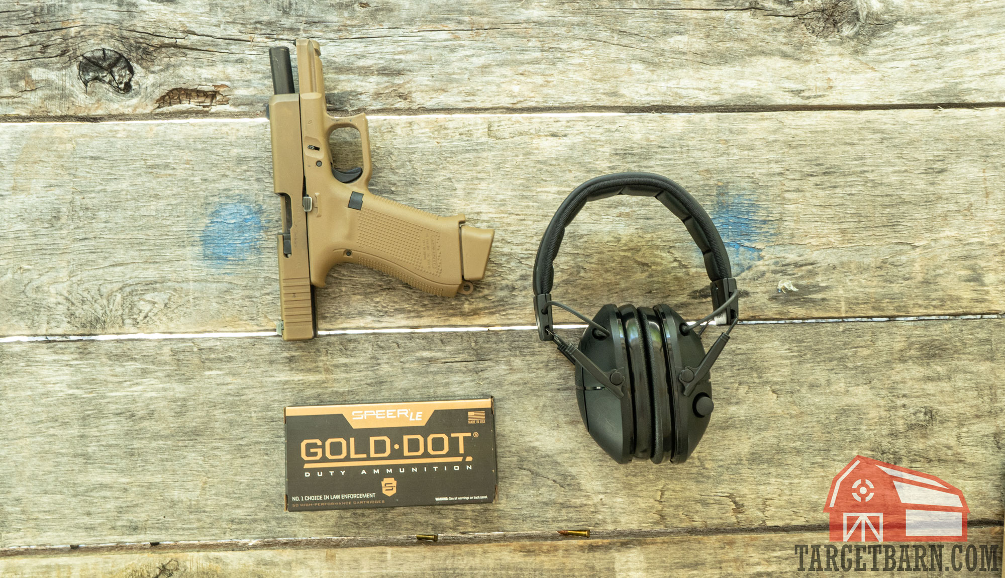 shooting range table a glock 19x, box of gold dot, and ear protection sitting on a table at the range