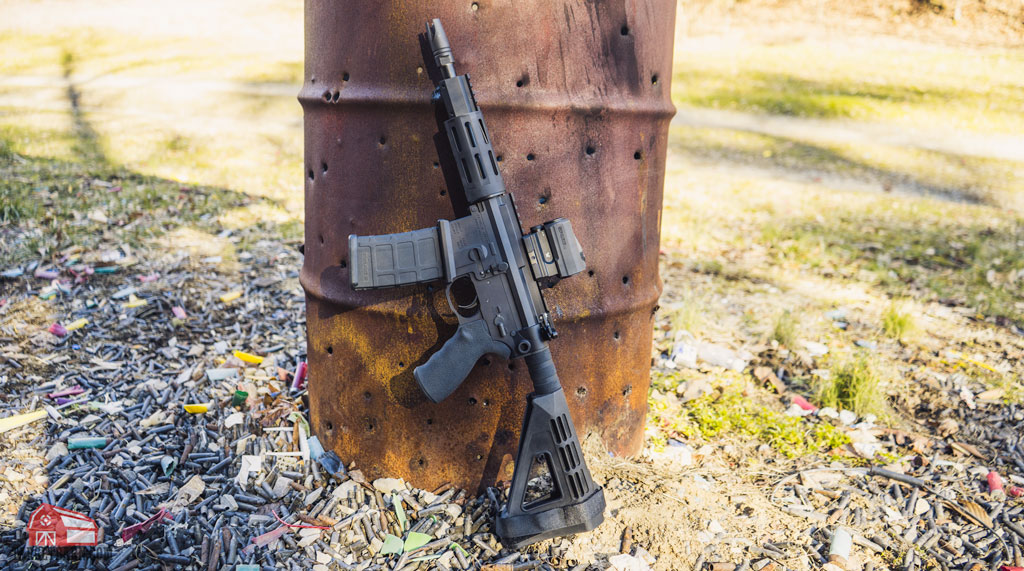 franklin armory sallus pdw leaning against a barrel with bullet holes