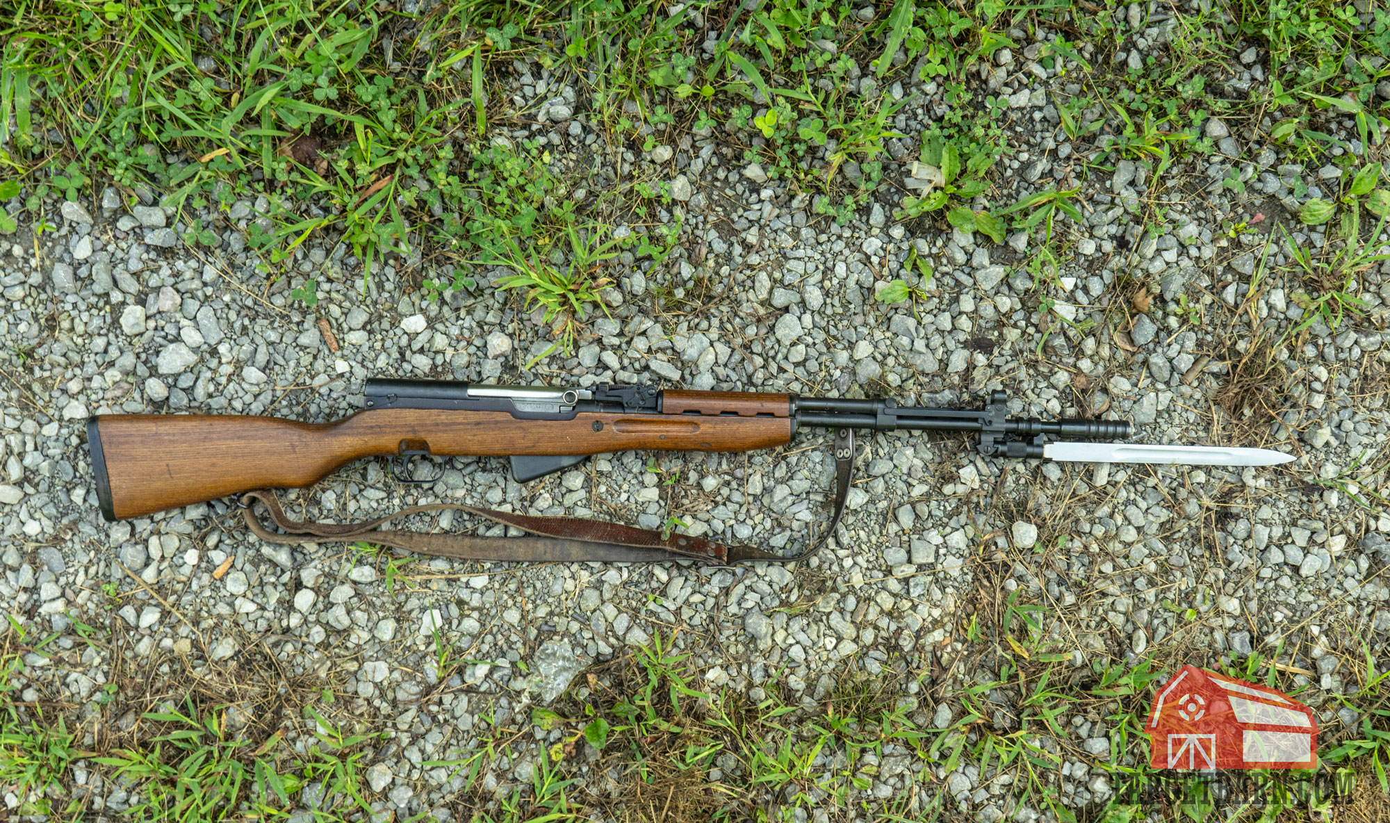 an sks rifle laying on the ground with bayonet extended
