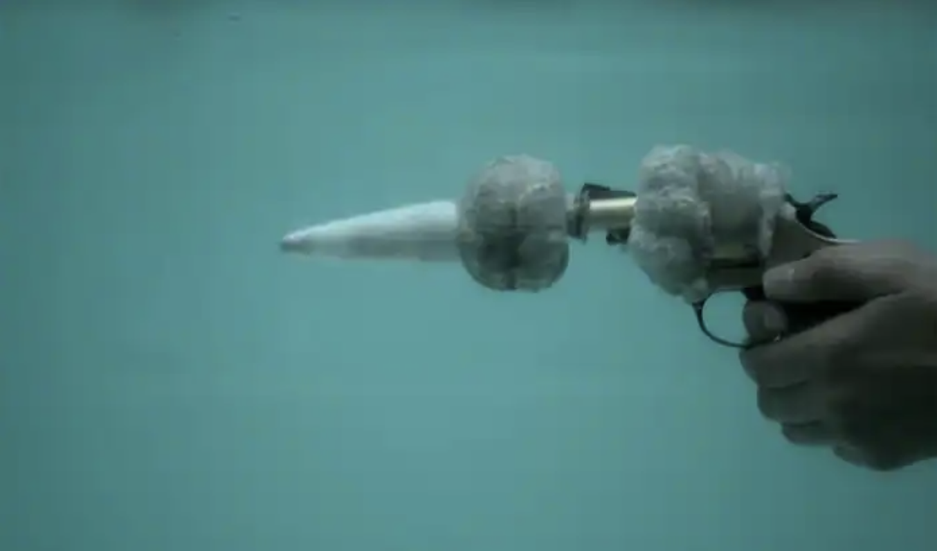 a stainless steel revolver being fired underwater