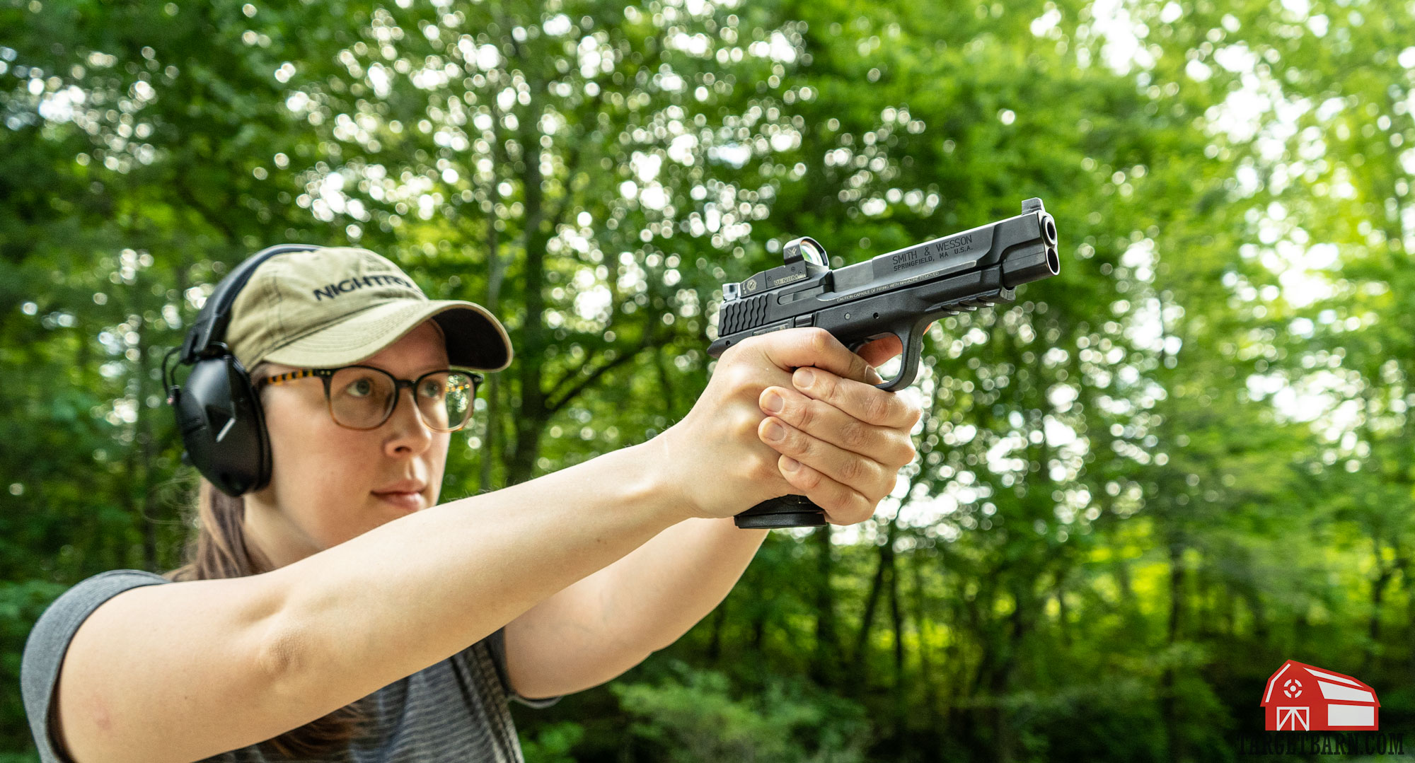 a woman shooting a pistol with a vortex venom red dot mounted